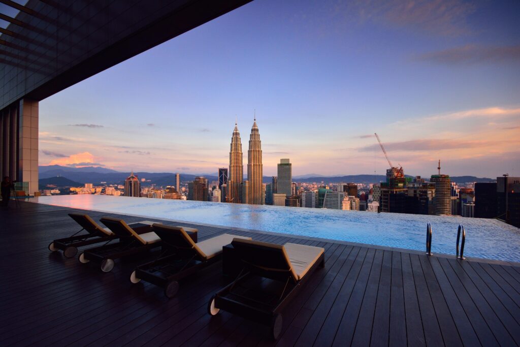 Relax by a luxury infinity pool with stunning Kuala Lumpur skyline and Petronas Towers at twilight.