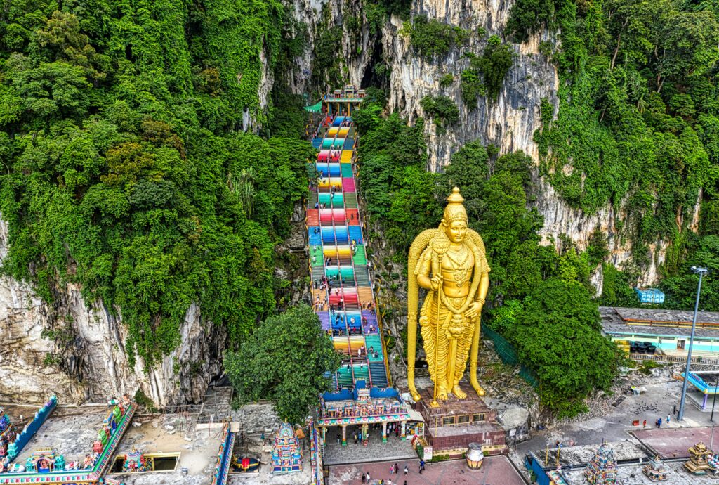 Aerial view of the vibrant Batu Caves and Lord Murugan statue in Selangor, Malaysia.