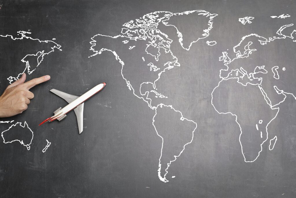 pexels-photo-3769118-3769118 Top view of miniature airplane placed on over gray world map with crop hand of anonymous person indicating direction representing travel concept